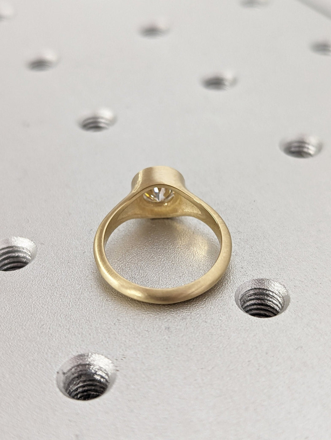 Profile view of round cut bezel engagement ring band
