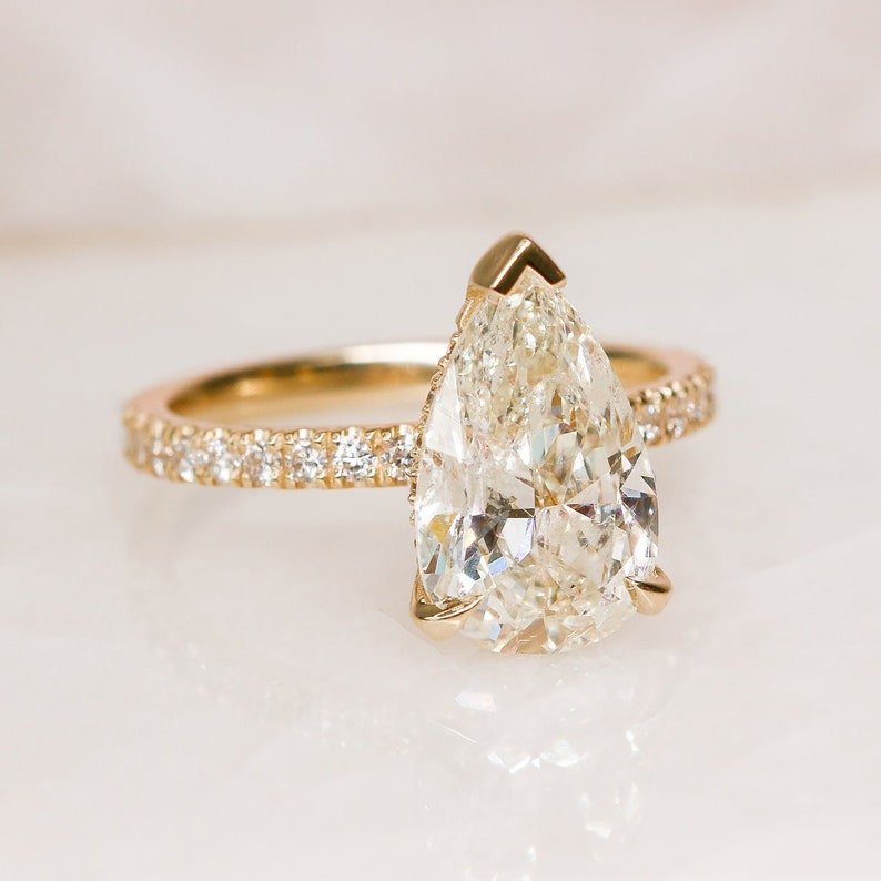 Detailed close-up of pear hidden halo diamond engagement ring