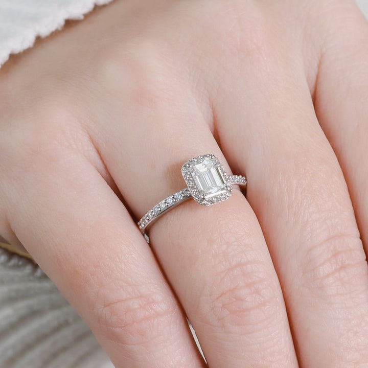Lifestyle shot of emerald halo diamond ring on hand