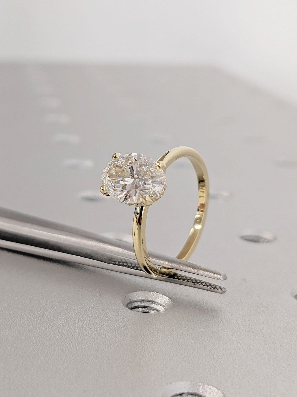 Oval hidden halo engagement ring viewed from the side