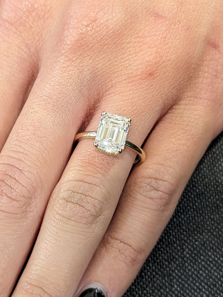 Emerald hidden halo engagement ring shown on hand for true-to-life sizing