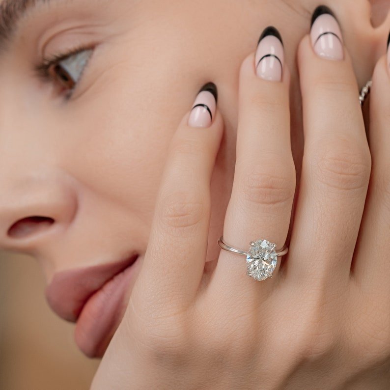 Oval hidden halo diamond ring displayed on jewelry stand