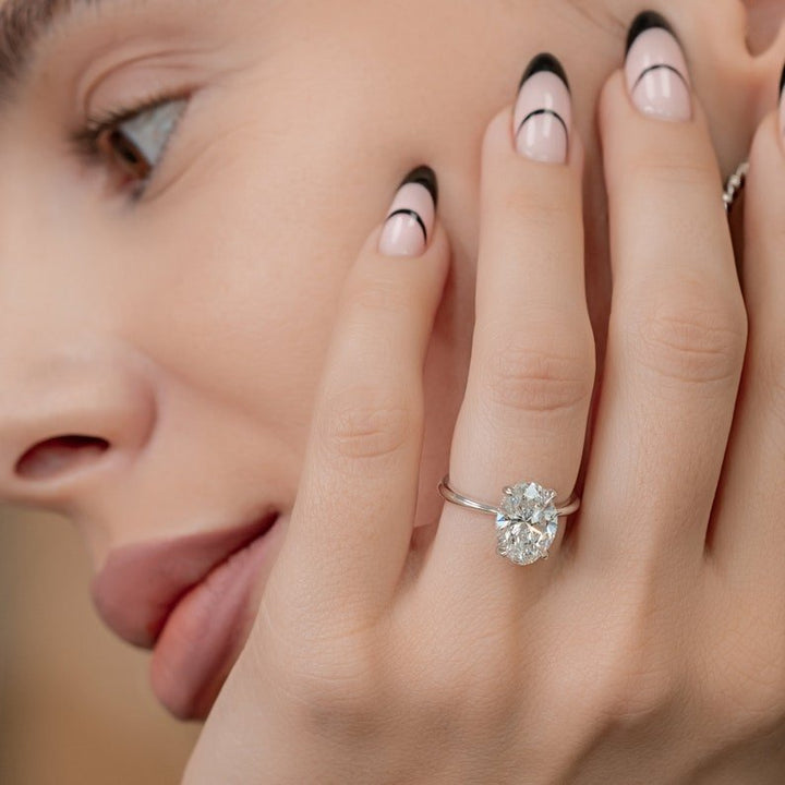Oval hidden halo diamond ring displayed on jewelry stand