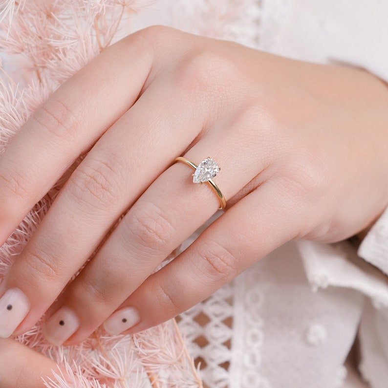 Pear hidden halo diamond engagement ring available in multiple metals