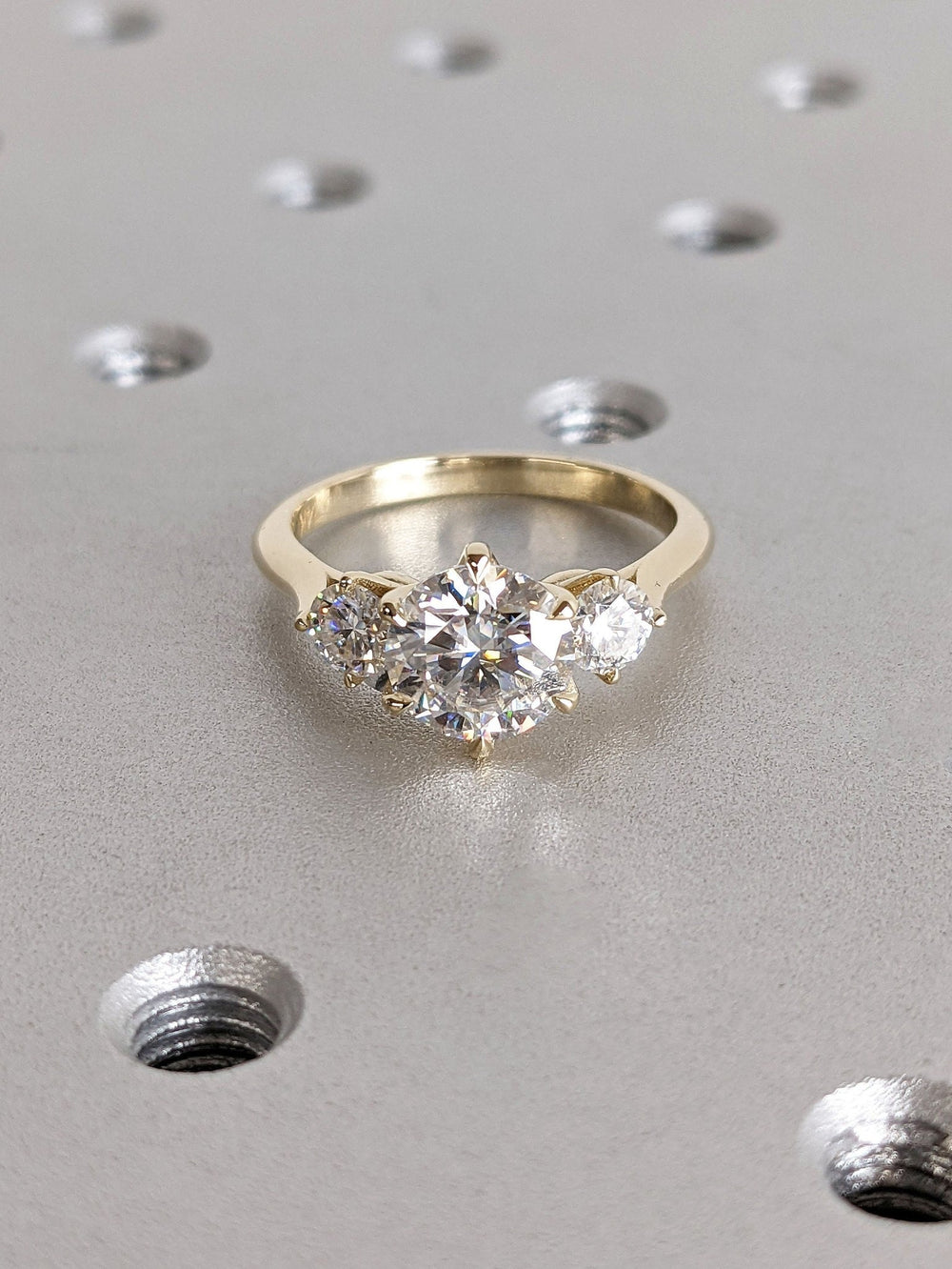 Certified round cut diamond featured in three stone engagement ring