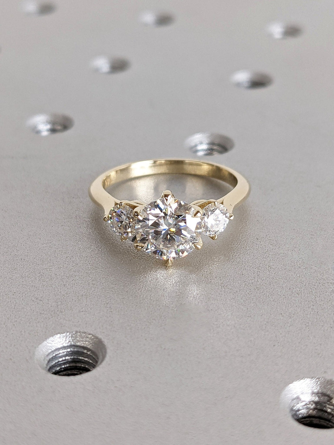 Certified round cut diamond featured in three stone engagement ring