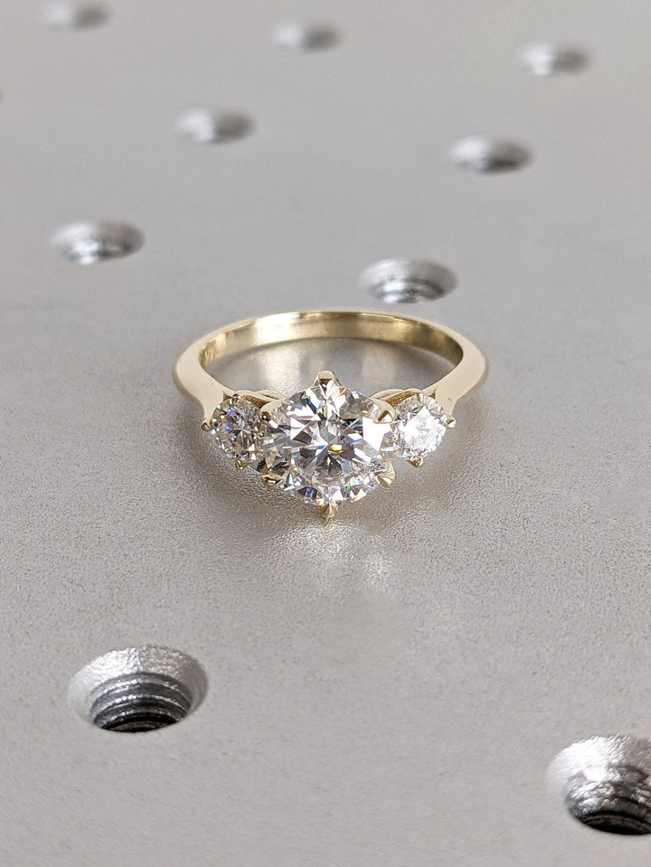 Certified round cut diamond featured in three stone engagement ring