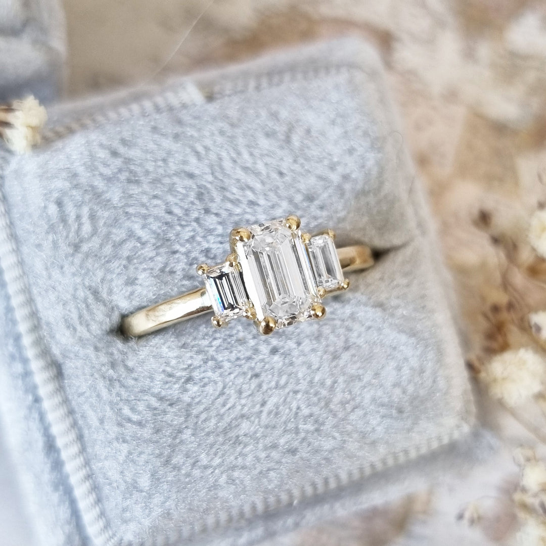 Lifestyle shot of emerald three stone diamond ring on hand