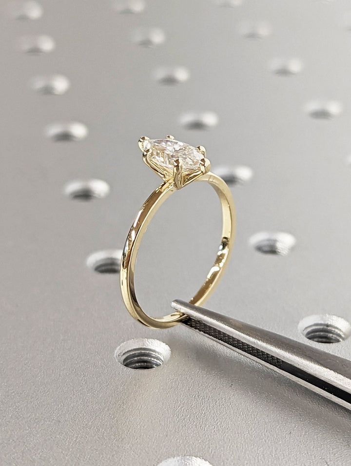 Marquise solitaire engagement ring shown on hand for true-to-life sizing