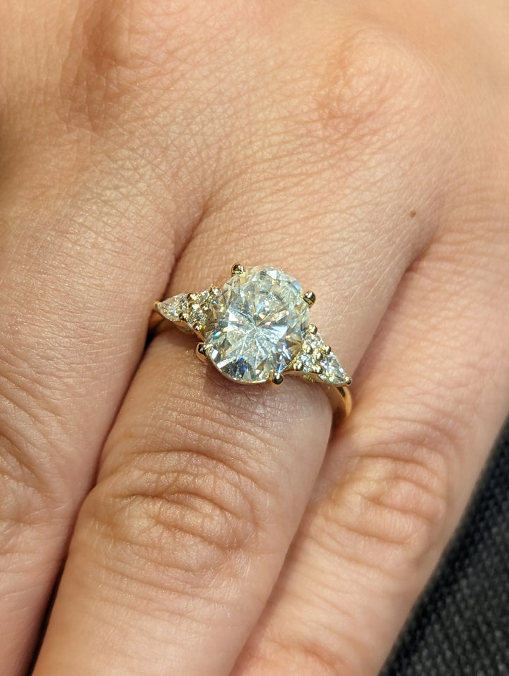 Oval cluster engagement ring shown on hand for true-to-life sizing