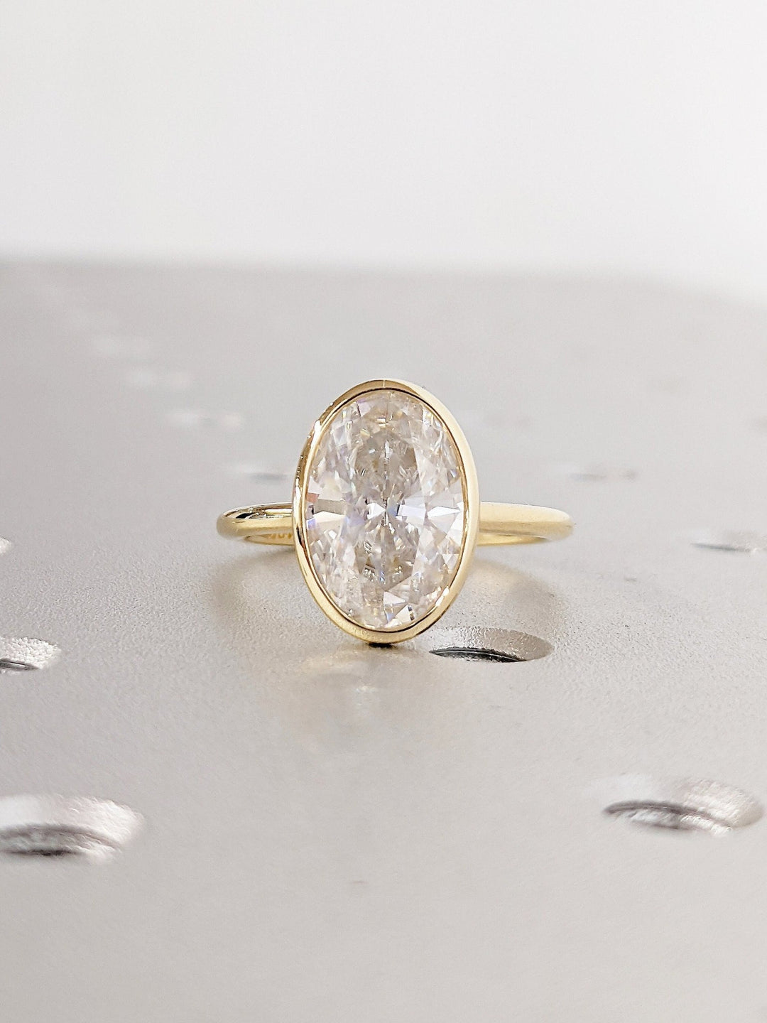 Certified oval cut diamond featured in bezel engagement ring