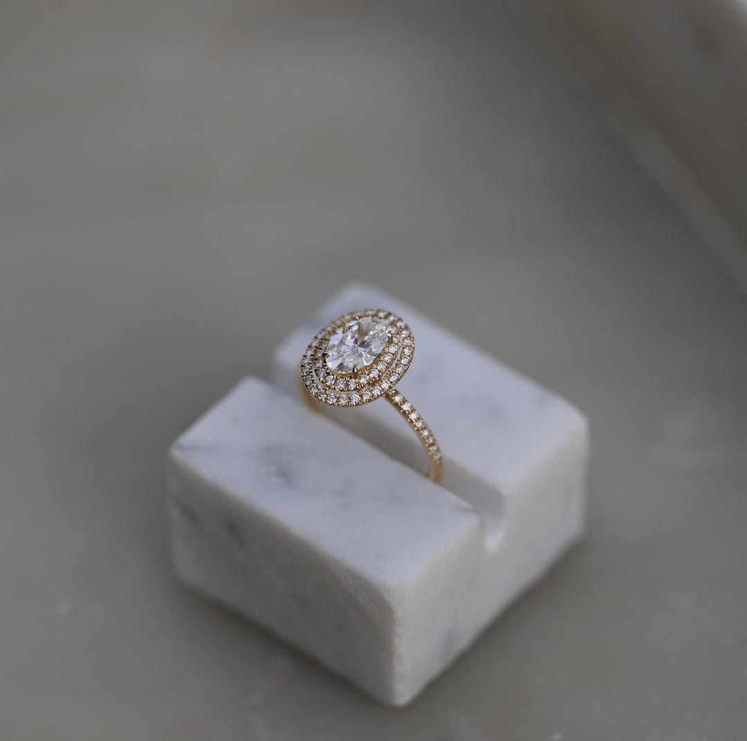 Oval halo engagement ring shown on hand for true-to-life sizing