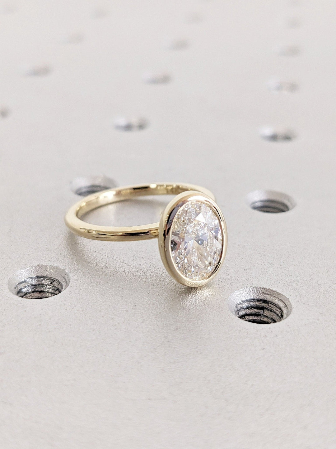 Angled view of oval cut diamond in bezel setting