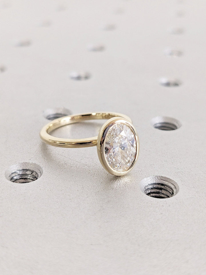 Angled view of oval cut diamond in bezel setting