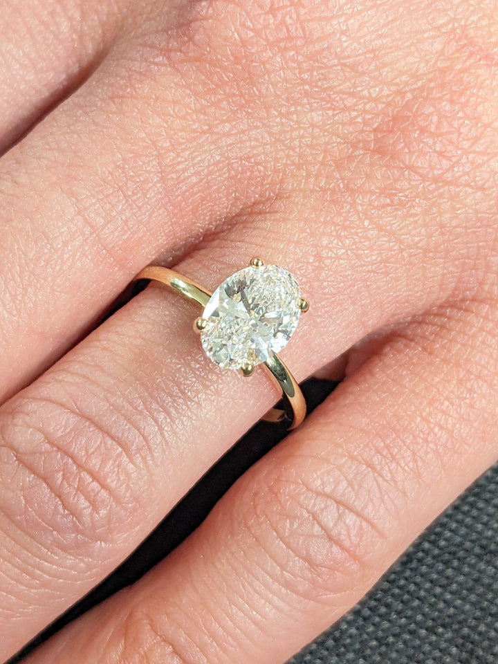 Oval hidden halo engagement ring shown on hand for true-to-life sizing