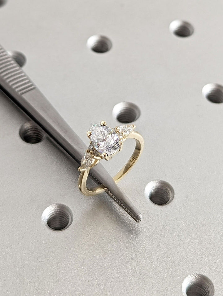 Pear cluster engagement ring shown on hand for true-to-life sizing