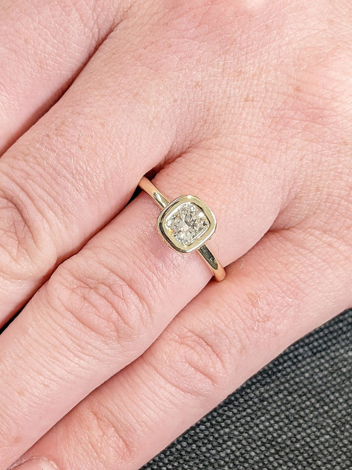 Cushion hidden halo diamond ring displayed on jewelry stand