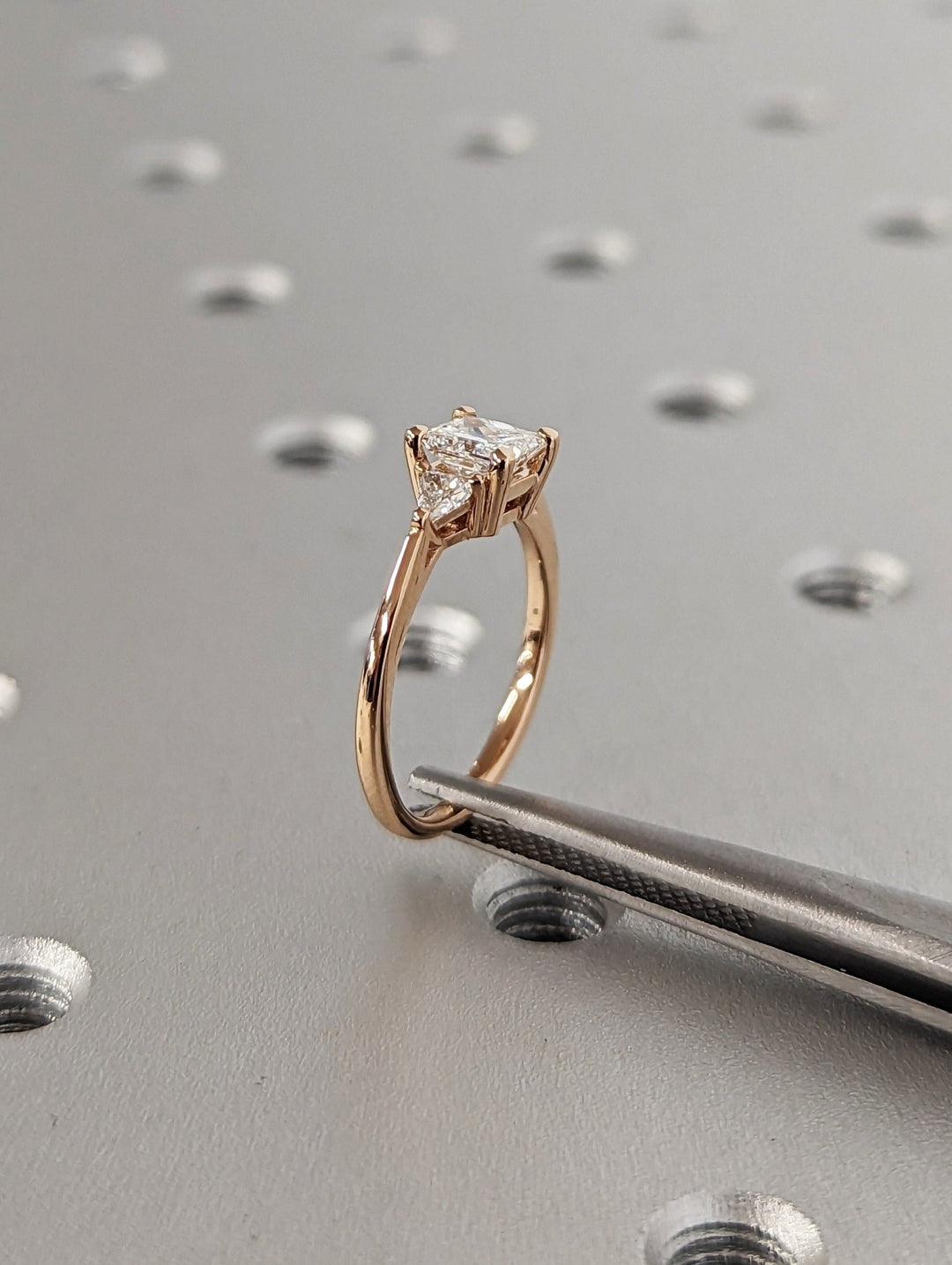 Princess three stone diamond ring displayed on jewelry stand