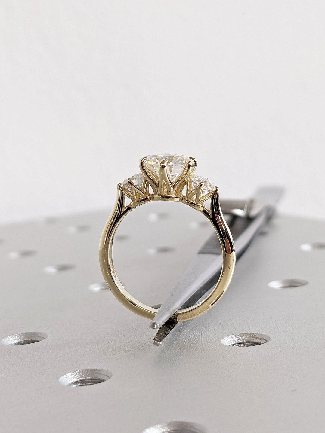 Round three stone diamond engagement ring available in multiple metals