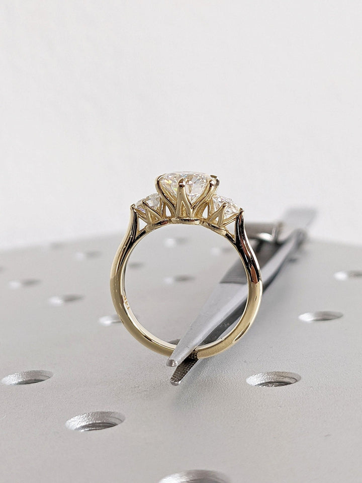 Round three stone diamond engagement ring available in multiple metals