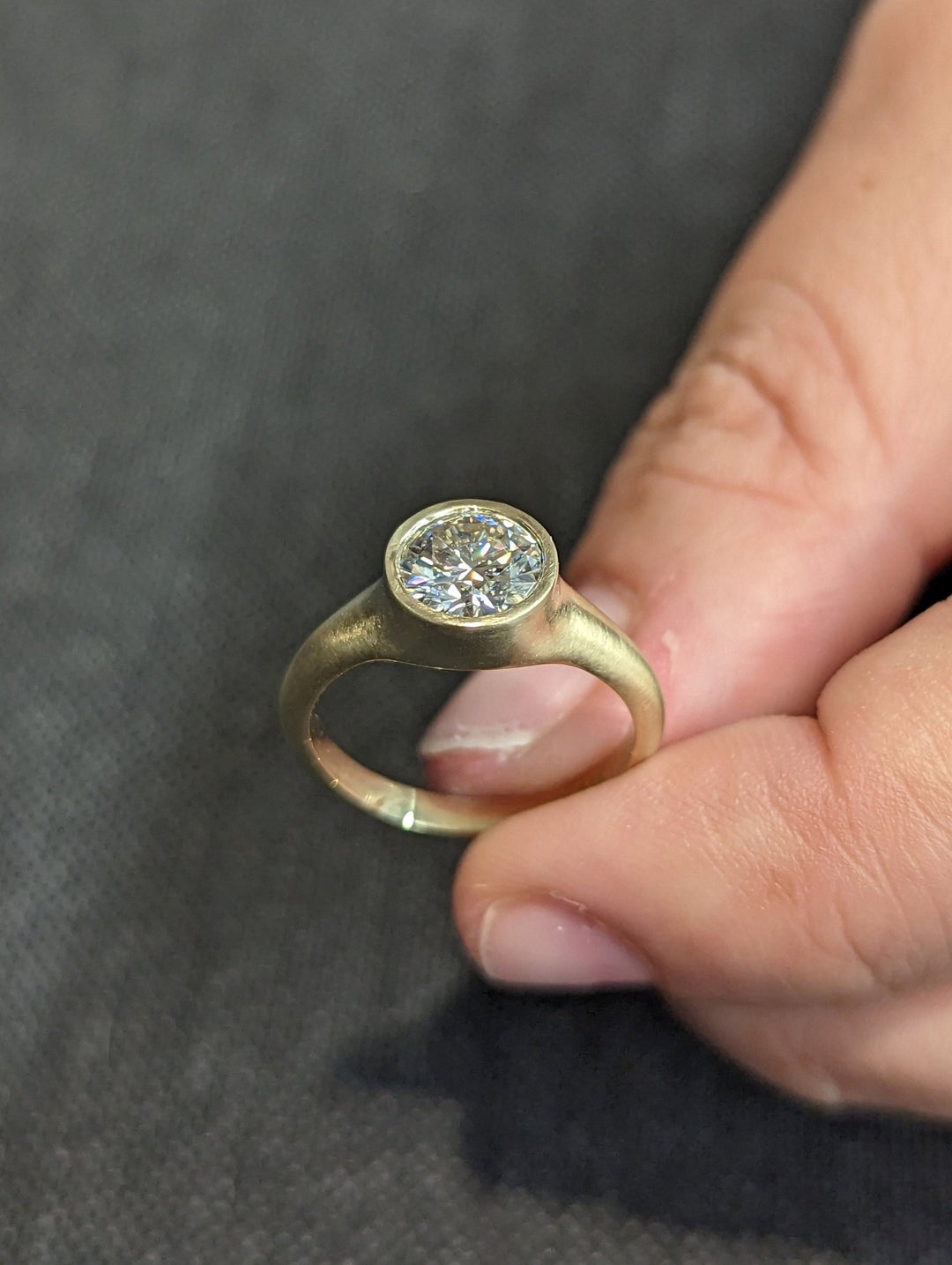 Close-up of round cut center diamond in bezel engagement ring