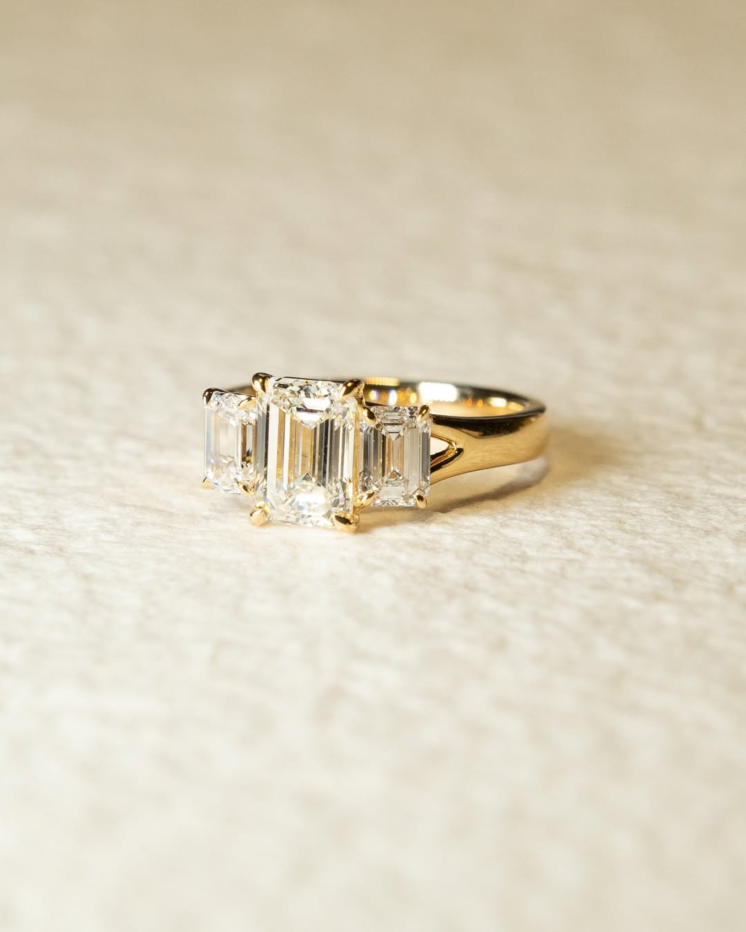 Emerald cut three stone engagement ring shown in real-life wear