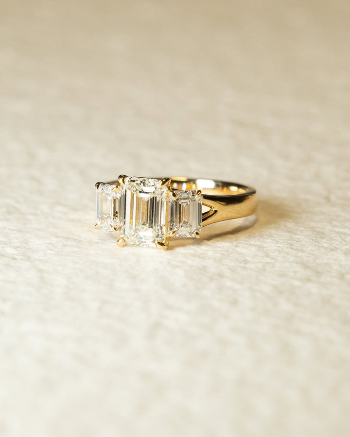Emerald cut three stone engagement ring shown in real-life wear