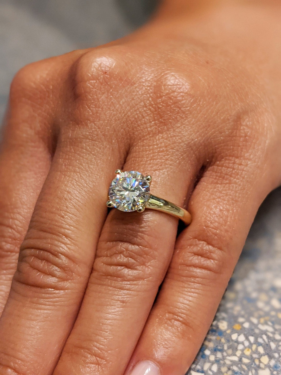 Round solitaire engagement ring shown on hand for true-to-life sizing