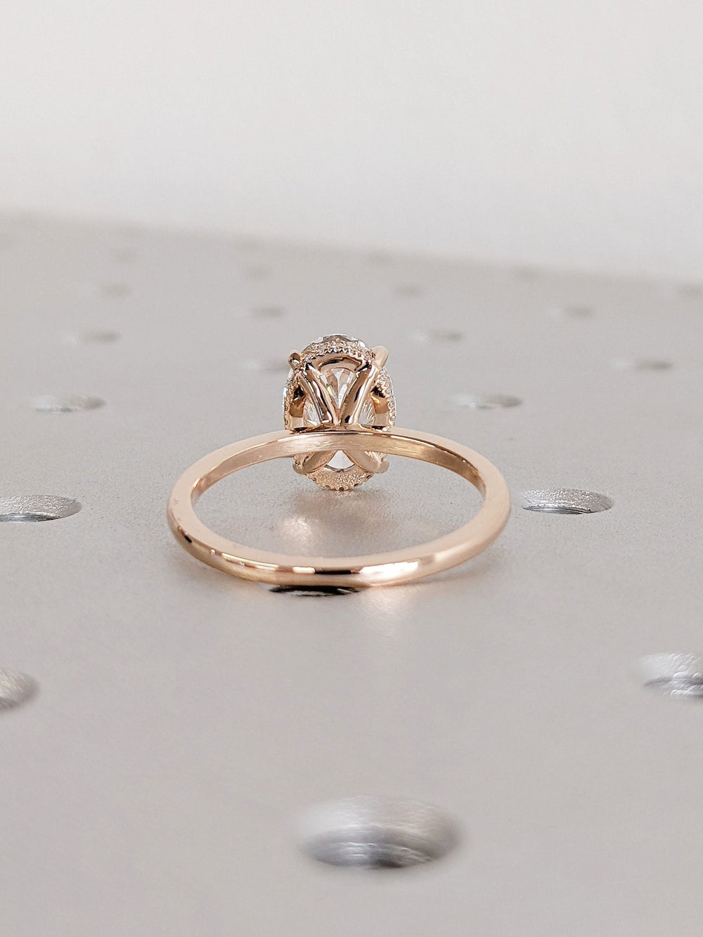 Oval hidden halo engagement ring shown on hand for true-to-life sizing