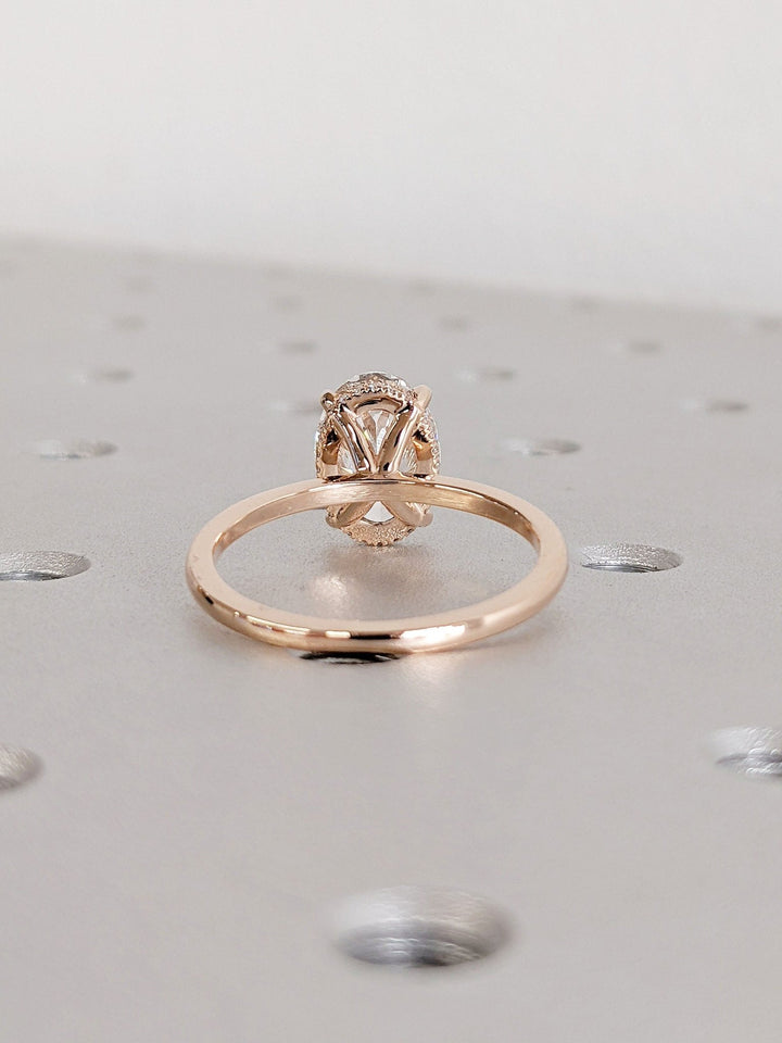 Oval hidden halo engagement ring shown on hand for true-to-life sizing