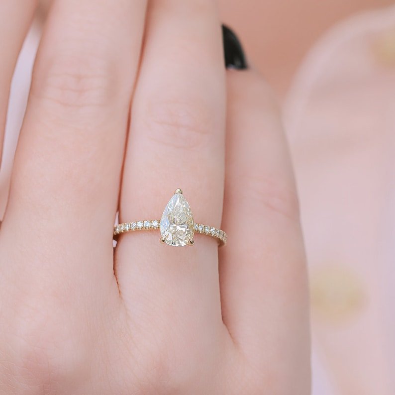 Pear hidden halo engagement ring shown on hand for true-to-life sizing
