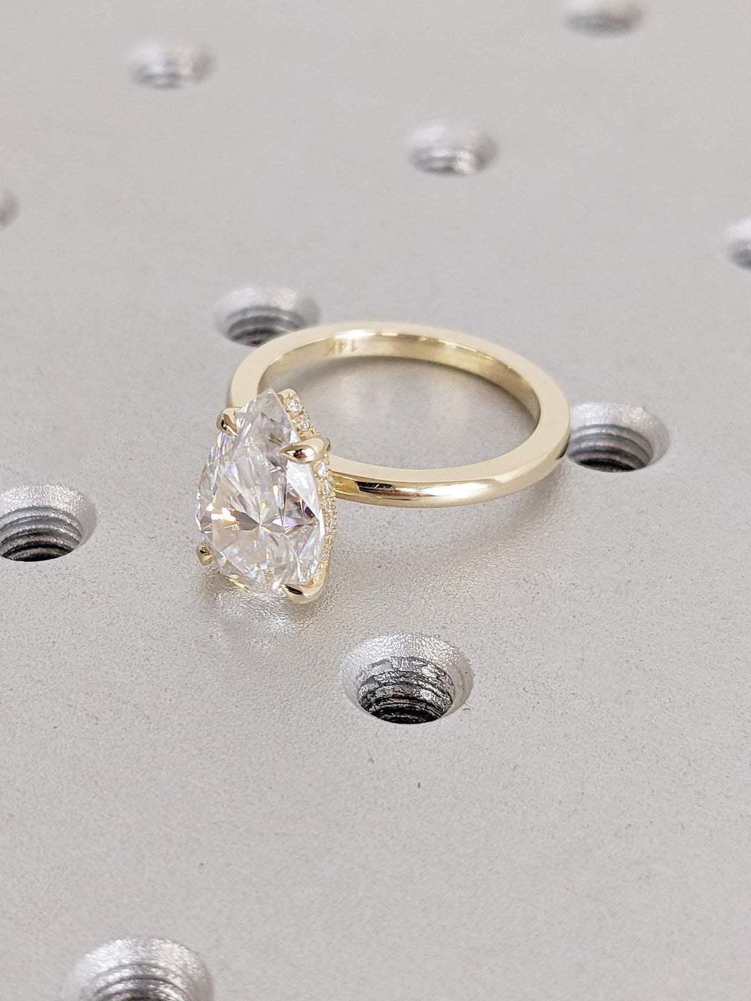 Pear hidden halo engagement ring offered in gold and platinum