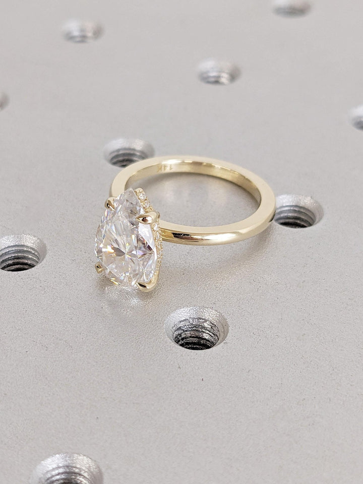 Pear hidden halo engagement ring offered in gold and platinum