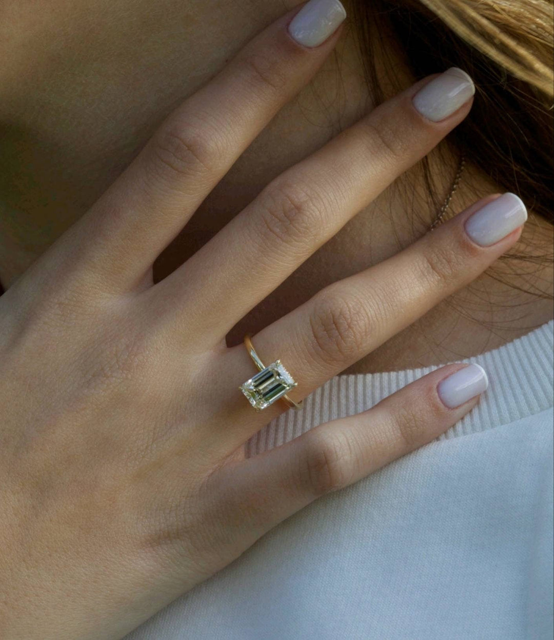 Emerald hidden halo engagement ring shown on hand for true-to-life sizing