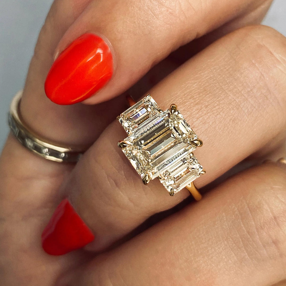 Certified emerald cut diamond featured in three stone engagement ring