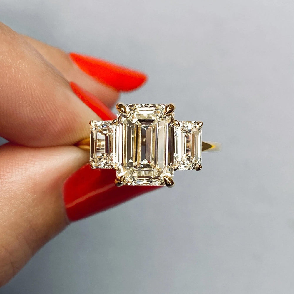 Emerald three stone diamond ring displayed on jewelry stand