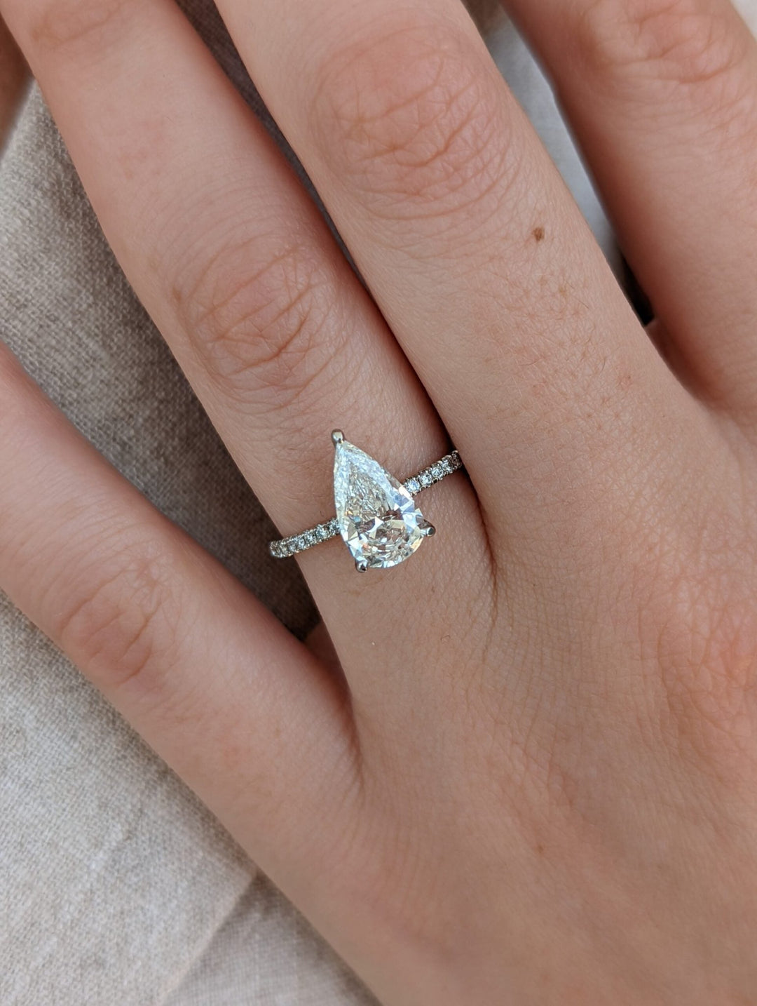 Close-up of pear cut center diamond in pave engagement ring